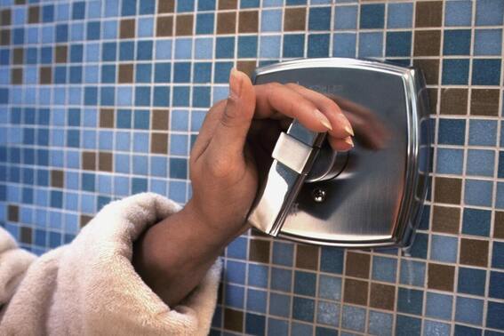 Hand reaching to turn off shower, how to save water and energy in the bathroom